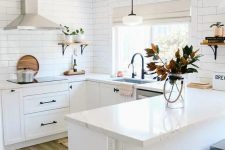 a white farmhouse U-shaped kitchen with a white subway tile backsplash and white stone countertops