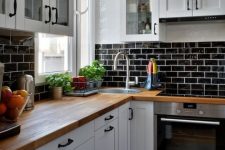 a white farmhouse kitchen with a black glazed tiles, butcherblock countertops, black pendant lamps