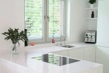 a white minimalist L-shaped kitchen with a matching hood and a window and a view is very airy and welcoming