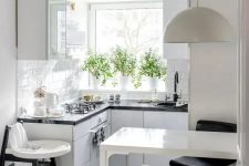 an airy Scandi kitchen with black countertops, a bar countertop and stools plus a kid’s chair
