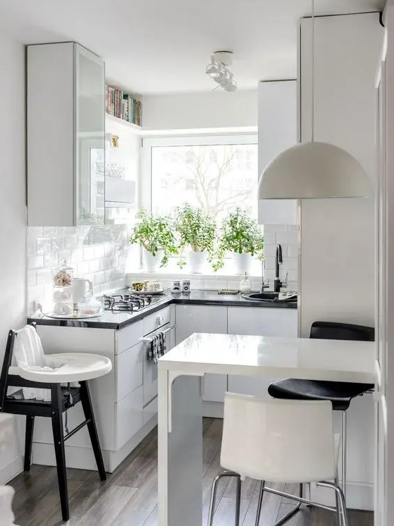 an airy Scandi kitchen with black countertops, a bar countertop and stools plus a kid's chair