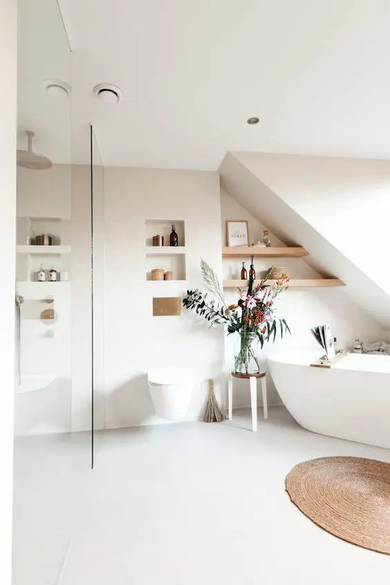 an airy Scandinavian bathroom with an oval bathtub, a shower space, niches and shelves, some lovely decor