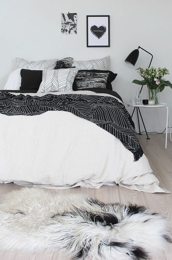 An airy Scandinavian bedroom with just some black touches for soem drama   a lamp, bedding and an artwork