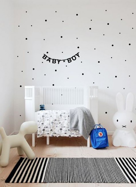 an airy Scandinavian kid's room with a polka dot wall, a white bed, some printed textiles and cool and simple toys