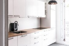 an airy Scandinavian kitchen with white cabinets, butcherblock countertops, a geometric floor and pendant lamps