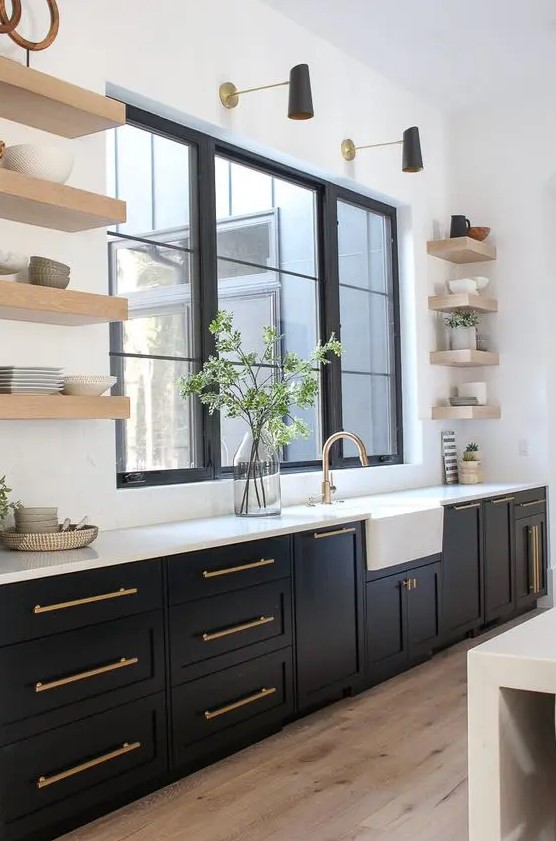 An elegant black farmhouse kitchen with open floating shelves, a white backsplash and countertop plus brass touches.