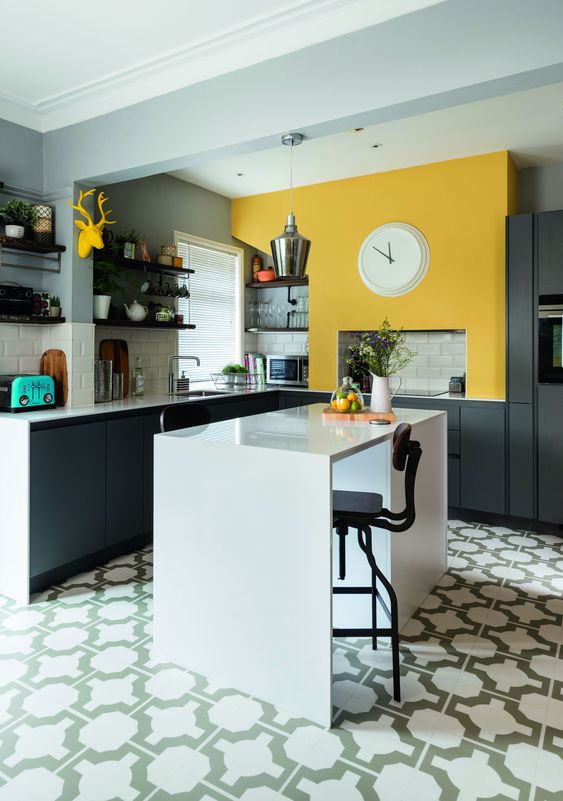 an elegant modern kitchen with graphite grey cabinets, a sunny yellow wall and a white kitchen island