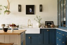 an elegant navy L-shaped kitchen with shaker style cabinets, a white kitchen island and table, a gallery wall and some decor