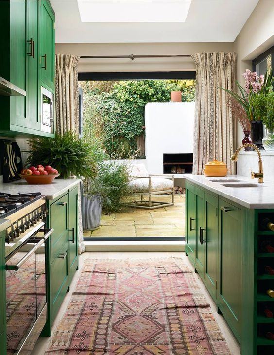 an emerald galley kitchen with shaker cabinets, white stone countertops, a bold boho rug, an entrance to the terrace