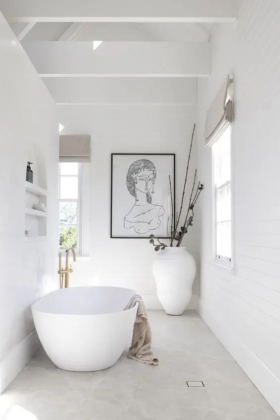 An eye catchy Scandinavian bathroom with shiplap, a niche with shelves, an oval tub, an artwork, a vase with branches