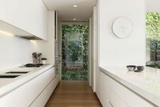 an ultra-minimalist white kitchen with sleek cabinets and built-in lights, everything hidden for a clean look