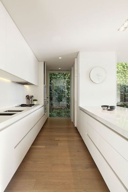 an ultra minimalist white kitchen with sleek cabinets and built in lights, everything hidden for a clean look