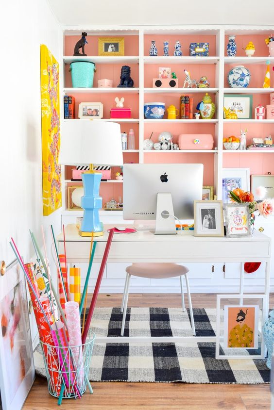 a chic home office with a pastel pink storage unit, a bold yellow artwork, white furniture and blooms feels spring like
