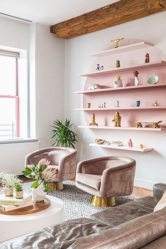 a pastel living room with a pink open shelving unit, refined taupe furniture and potted blooms and greenery