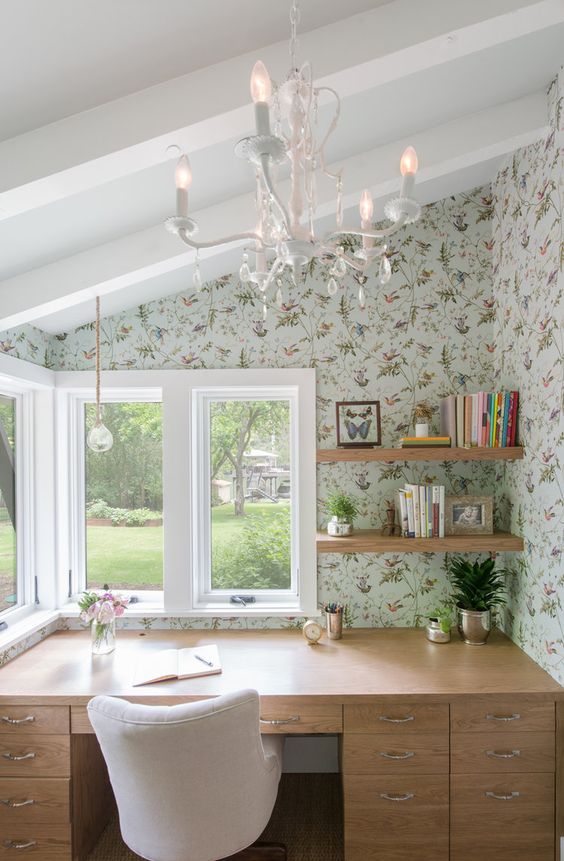 12 a cute attic home office with a desk, open shelves and floral wallpaper, a vintage chandelier and a white chair