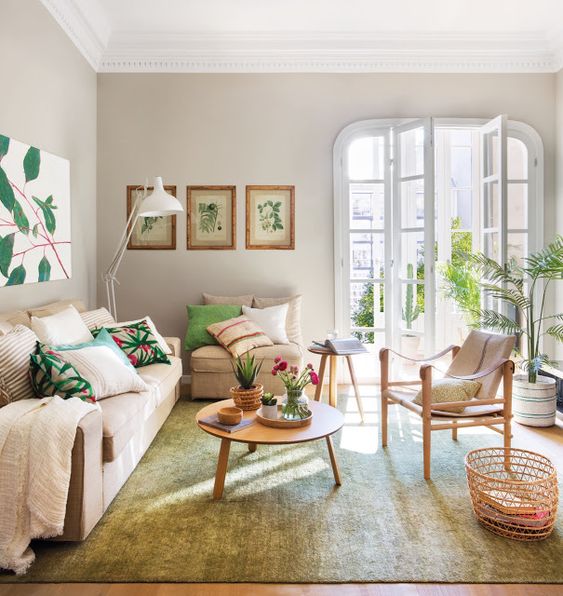 an airy and chic living room with neutral stylish furniture, floral print pillows, botanical artworks and an entrance to the balcony