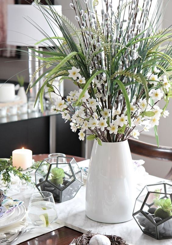a fresh spring centerpiece of white blooms, grasses, willow and mini terrariums with moss, pebbles and succulents