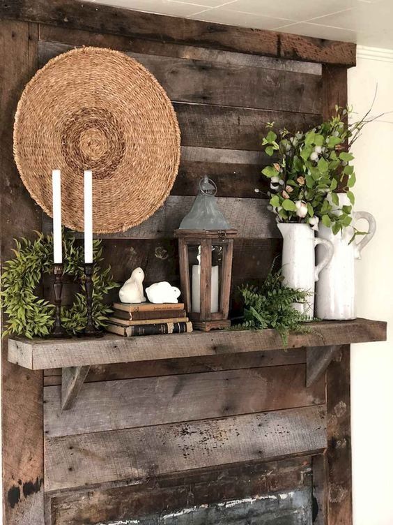 a rustic vintage spring mantel with candles, a greenery wreath, fern, greenery in jugs, a decorative woven plate and a candle lantern