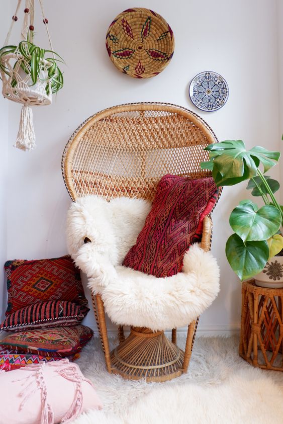 a 70s inspired peacock chair with faux fur and a red boho pillow is a chic piece for a boho modern room