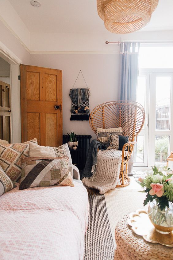a chic rattan peacock chair with pillows and blankets plus a chunky knit throw is a cool addition to your space