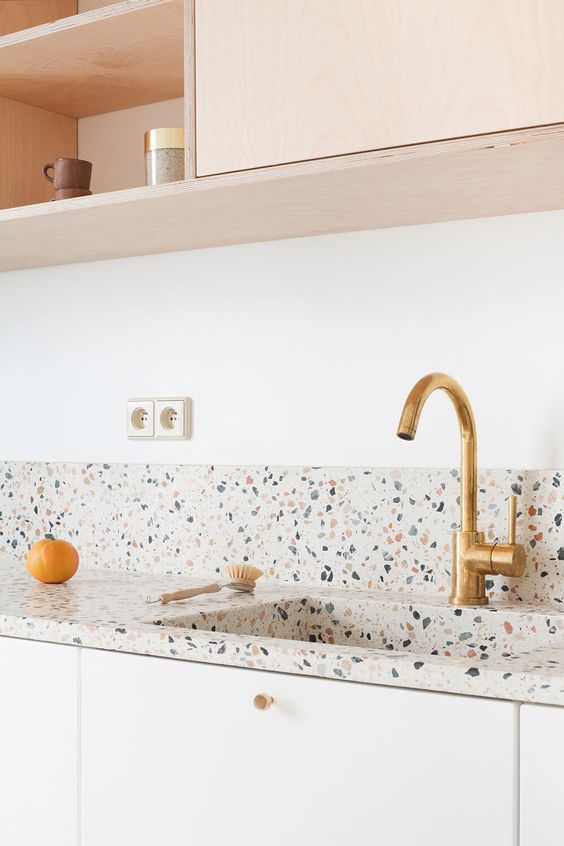 a blonde wood and white kitchen with a bright and fun terrazo countertop and a backsplash is a lovely space