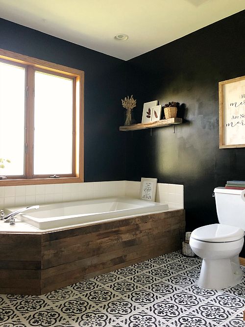 a catchy boho bathroom with a patterned floor and black walls, a bathtub clad with reclaimed wood is pretty