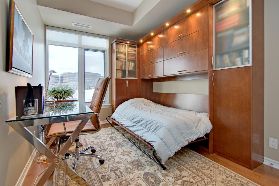 a home office combined with a guest bedroom – a large storage unit and a Murphy bed plus a glass desk and a leather chair