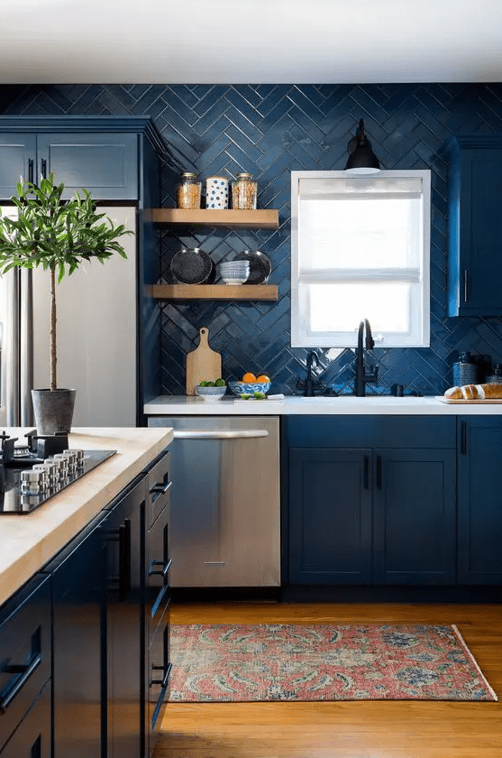 a navy farmhouse kitchen with shaker cabinets, white stone countertops, open shelves, a a fridge and some greenery