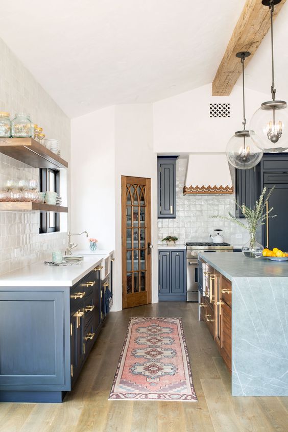 a navy farmhouse kitchen with white countertops, a stained kitchen island with a grey stone waterfall countertop is cozy