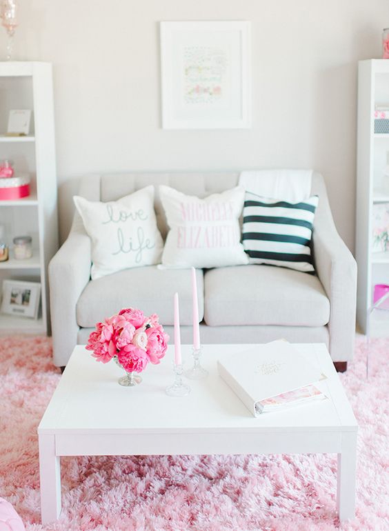 a neutral living room with a loveseat, a white table, pink touches is a cute and lovely space with a girlish feel