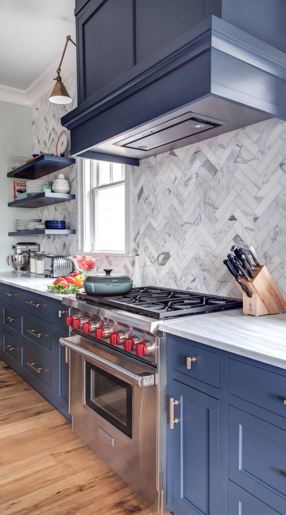 a refined blue kitchen with shaker cabinets, a marble herringbone tile backsplash, white countertops and open shelves