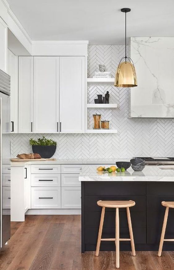 a refined contemporary kitchen with white cabinets and a black kitchen island, white quartz countertops and a white herringbone backsplash