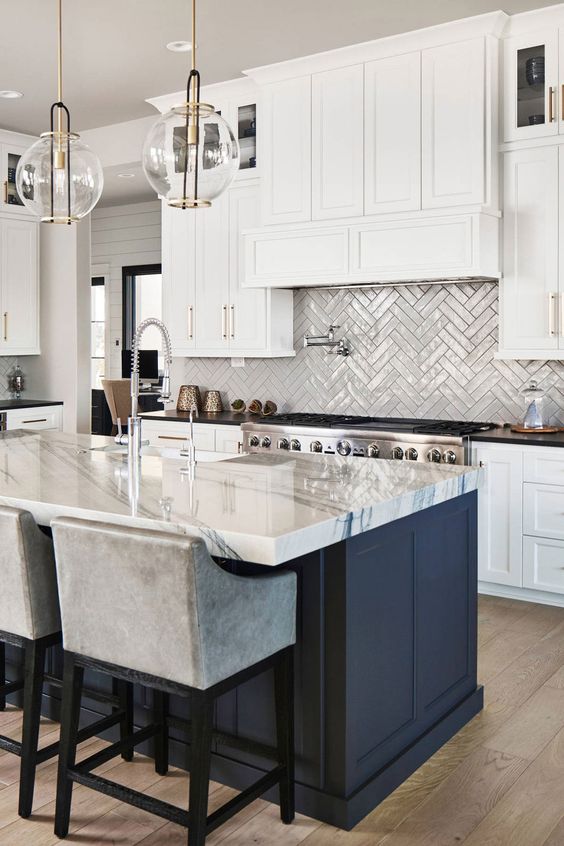 a refined modern kitchen with white cabinets, a navy kitchen island, black and white quartz countertops, a grey herringbone tile backsplash