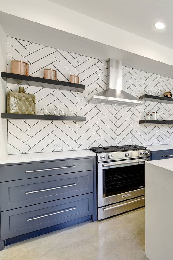 a refined navy kitchen with a white oversized backsplash and white countertops plus black floating shelves is gorgeous