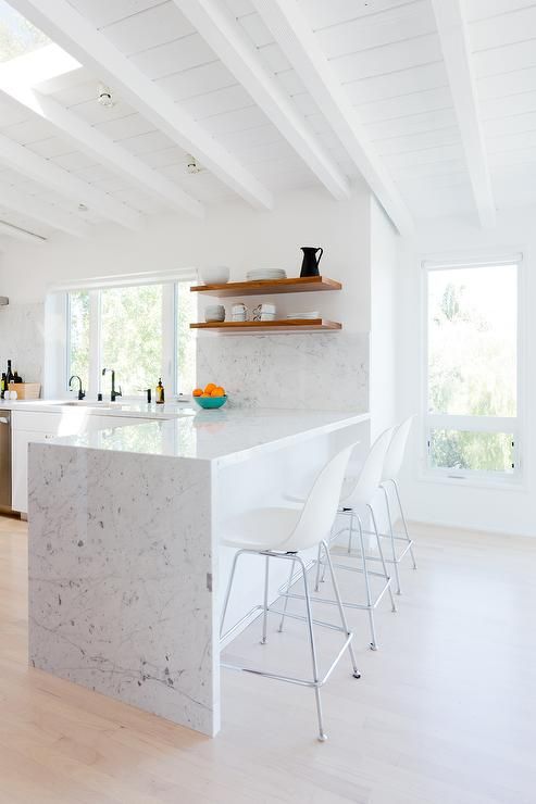 a serene and airy white kitchen with a built-in kitchen island and a waterfall white stone countertop for more chic