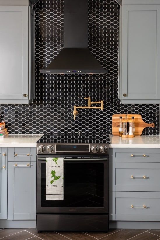 a stylish grey farmhouse kitchen with white coutnertops and a black hex tile backsplash plus a black hood looks very refined