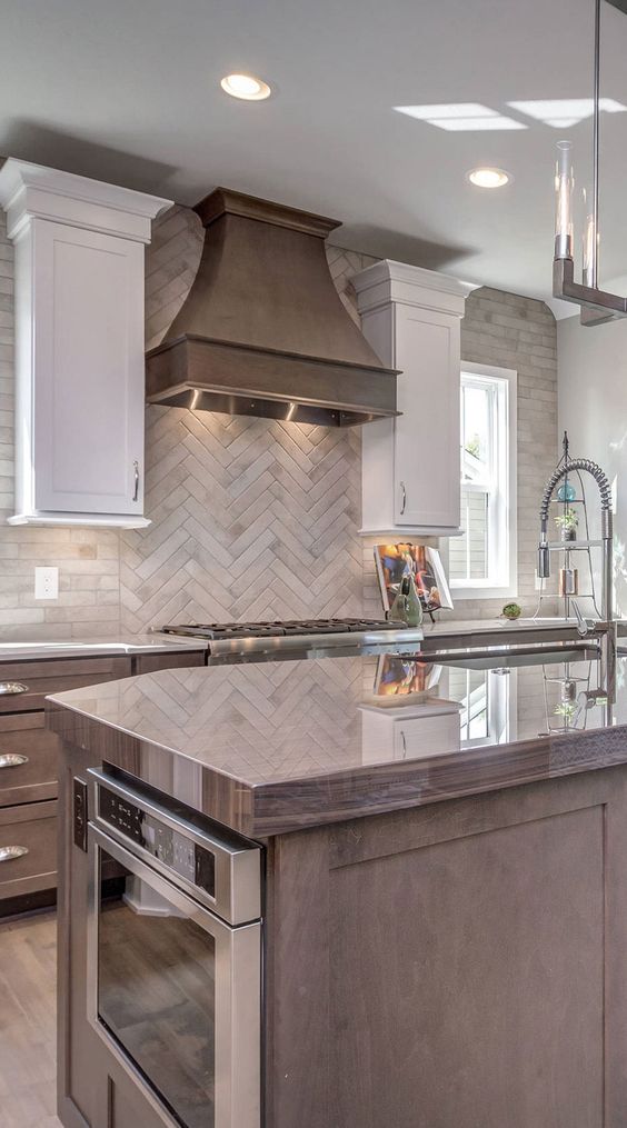 a vintage kitchen with stained cabinets, white upper ones, a beige herringbone tile backsplash and vintage appliances