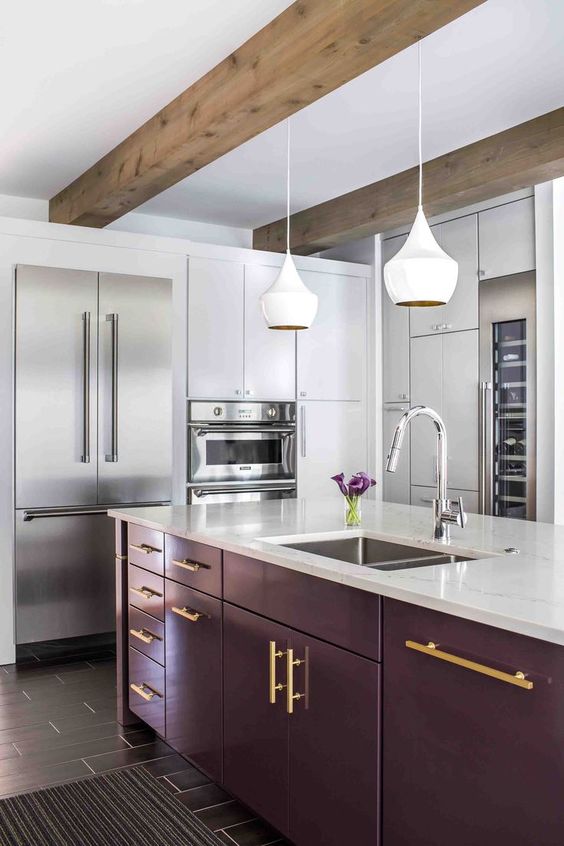 a white kitchen, a deep purple kitchen island, wooden beams, white pendant lamps and touches of gold