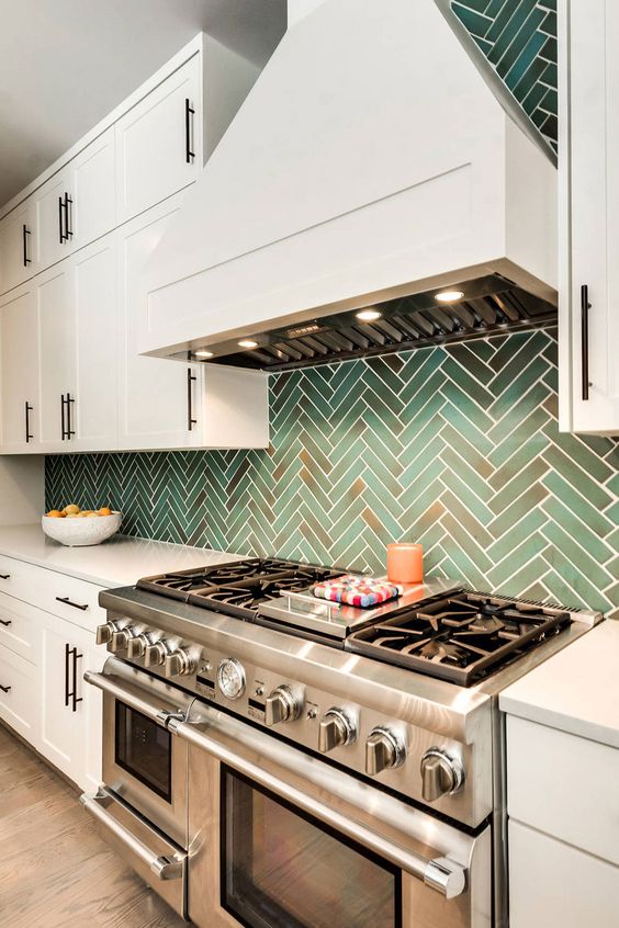 a white vintage kitchen with shaker cabinets, white countertops, a grene herringbone tile backsplash and built-in lights