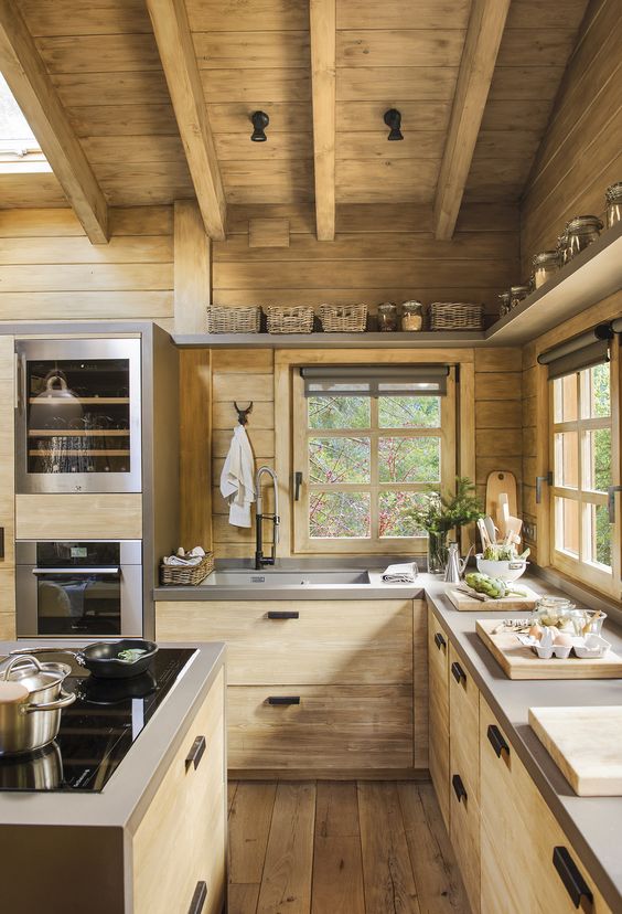 a wooden cabin kitchen with concrete countertops and wooden beams on the ceiling plus black handles and knobs