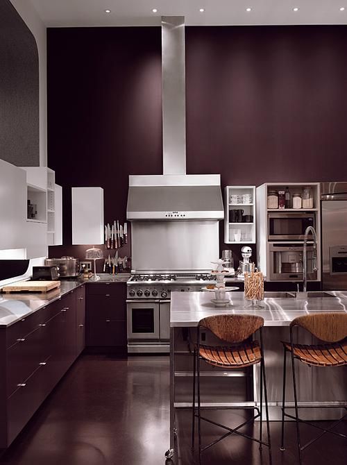 An elegant aubergine kitchen with grey countertops and stainless steel appliances plus a metal kitchen island