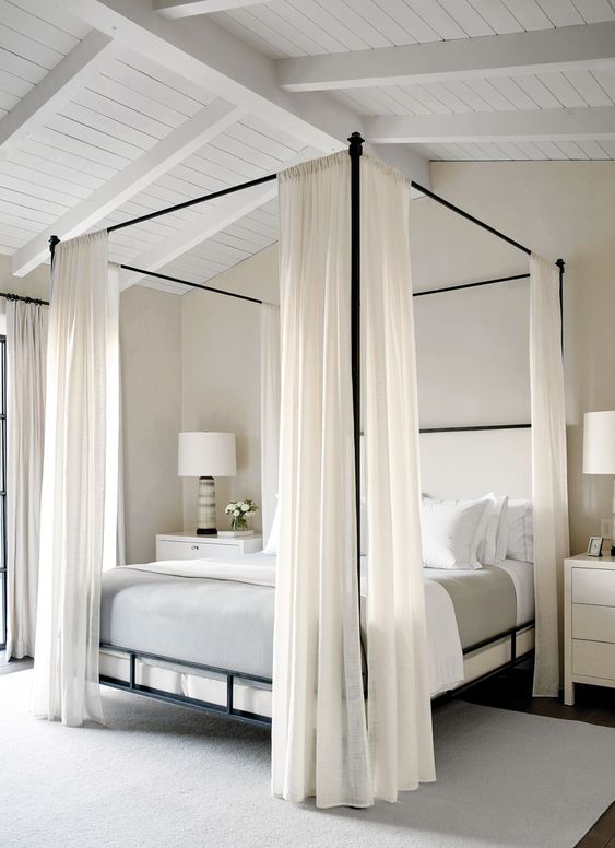 08 a stylish minimalist bedroom done in neutrals, with a canopy bed with curtains, white nightstands and table lamps and neutral bedding