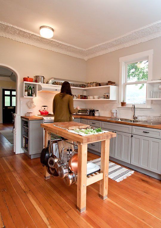 a grey farmhouse kitchen with butcherblock countertops, a wooden kitchen island with plenty of storage that looks airy