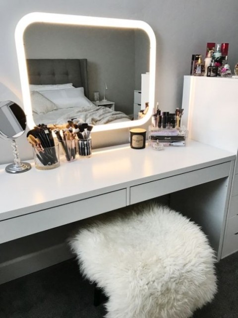 a Scandinavian beauty nook with an IKEA Micke desk as a vanity, a lit up mirror and some acrylic makeup storage