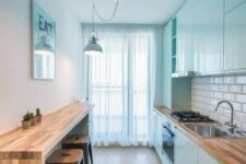a Scandinavian kitchen with sleek mint blue cabinets, a long breakfast bar, metal stools, pendant lamps and art