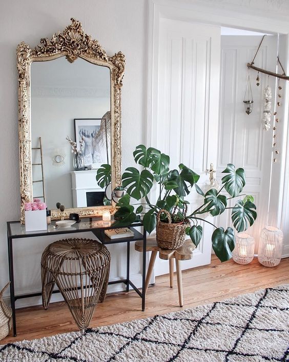 a chic makeup spot with an IKEA Micke desk, a rattan stool, a mirror in a vintage frame and a statement potted plant