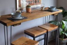 a cool breakfast bar with a tall table and stools, a bold artwork, a potted plant is a lovely idea for a modern kitchen