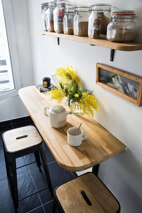 a farmhouse breakfast bar with a wall-mounted table, tall stools, a shelf, artwork is a cool and lovely space