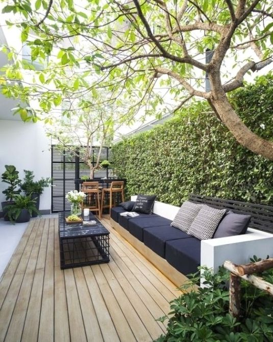 a modern outdoor sofa with black cushions and printed pillows, a black coffee table for a lovely outdoor lounge