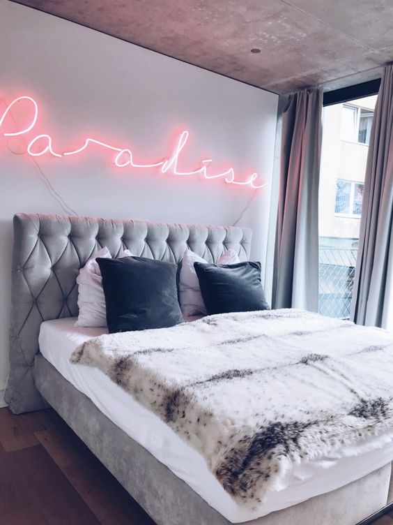 a modern refined bedroom accented wiht a pink neon light makes the space more whimsical and cool